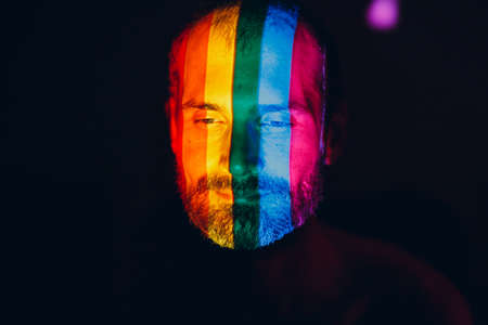 Rainbow Flag on face of adult man in dark.の写真素材