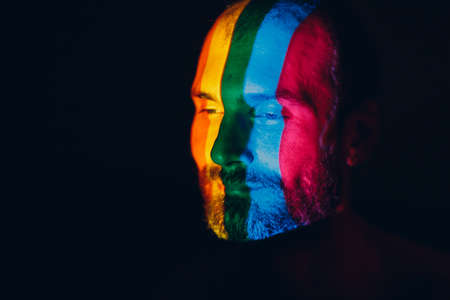 Rainbow Flag on face of adult man in dark.の写真素材