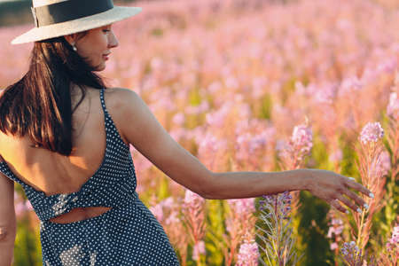 Girl in hat on blooming Sally flower field. Lilac flowers and woman.の写真素材