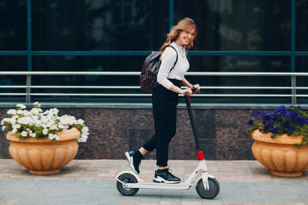 Young woman driving electric scooter at the cityの写真素材