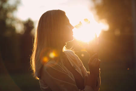 Happy young woman holds fall leaves in hand at autumn parkの写真素材