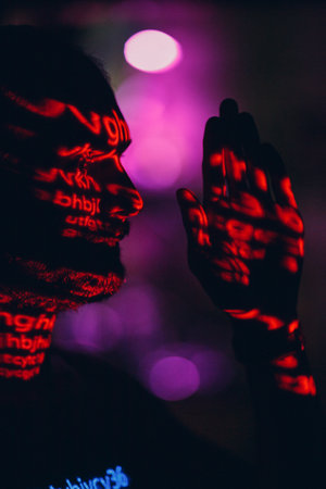 Young man with red letters on his face in the dark.の写真素材