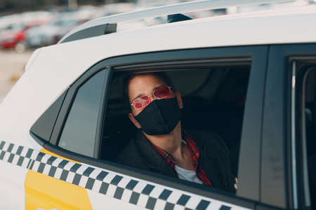 Man passenger in protective face medical mask in the taxi car during an epidemic quarantine city....