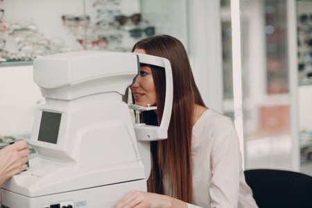 A woman doctor and patient doing opthalmology check vision test by refractometer
