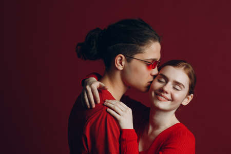 Beautiful young smiling couple hugging on red background. Valentines day concept.