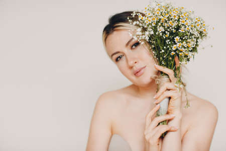 Young and beautiful blonde woman with daisies bouquetの写真素材