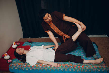 Thai man making classical thai massage procedure to young woman at beauty spaの写真素材
