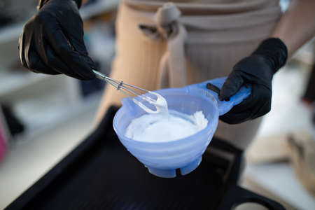 Young woman hairdresser dying hair at beauty salon. Professional hair roots coloring and mixing paint colorの写真素材