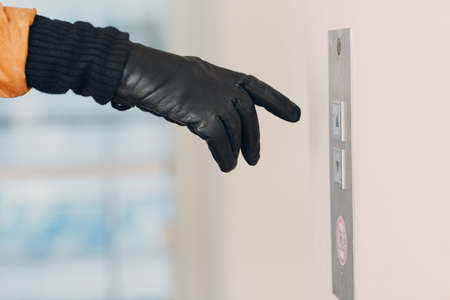 Close up of hand in glove forefinger pressing the button elevator during pandemic  quarantine conceptの写真素材