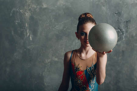 Young girl professional gymnast woman portrait rhythmic gymnastics with ball at studioの写真素材