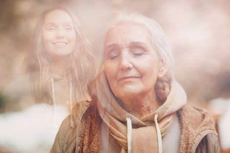 Grandmother and granddaughter women double exposure image. Young and elderly woman portrait. Love, generation, dreams and happy family relationsの写真素材