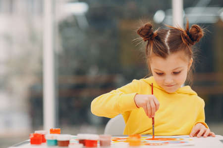 Little girl drawing art picture. Painting with brush and watercolor paints.