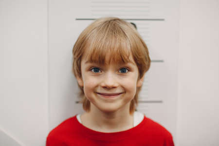 Children little boy are measured growth height at wall scale. Kid smile portrait.の写真素材