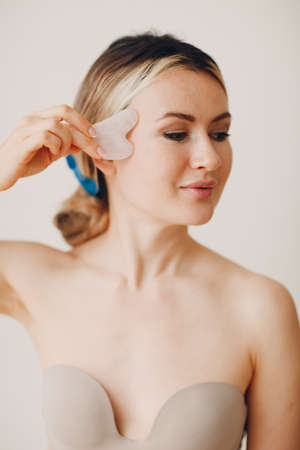 Young adult woman doing face guasha treatment massageの写真素材