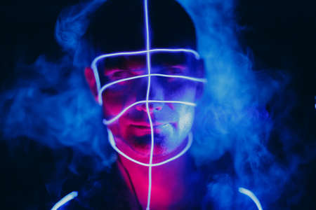 Portrait of man with neon red blue glow lines on his face. Concept cyberpunk and virtual realityの写真素材
