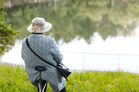 Elderly senior woman sitting in summer near lake pond. Happy old age conceptの写真素材