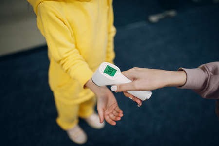 Child hand temperature measurement check by laser thermometer at kindergartenの写真素材