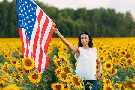 Young woman with American flag in the sunflower field. 4 of July Independence Day USAの写真素材