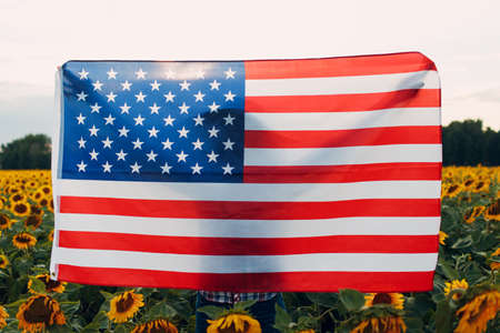 Young woman with American flag in the sunflower field. 4th of July Independence Day USA conceptの写真素材