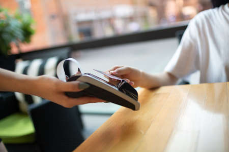 Close up hand of Woman pay with credit card contactless payment terminal cashier in outdoor cafe.の写真素材