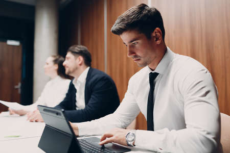 Businessman using working with laptop sits at table at office meeting. Business people man and woman...