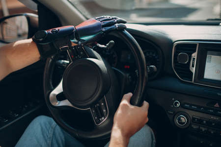 Young disabled man driver with artificial prosthetic hand driving on steering wheel vehicle carの写真素材
