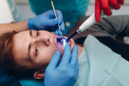 Dentistry. Dentist and patient. Light curing seal. UV dental lamp and orange protect glass.の写真素材