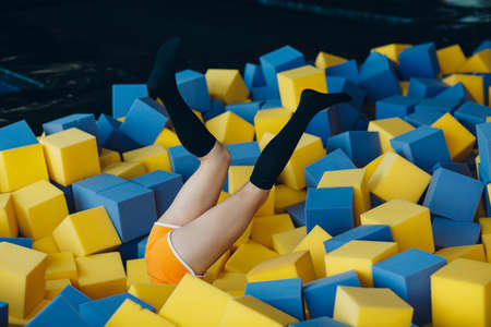 Young and beautiful woman plays in dry pool with cubes.の写真素材
