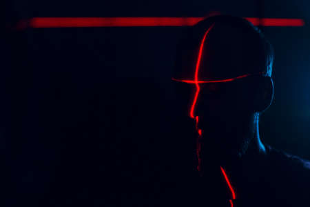 Man in dark with face illuminated by scan red laser on contour.