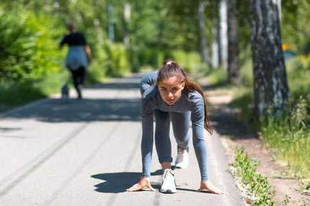 Athletic woman on track starting to run. Jogging pretty girl.の写真素材