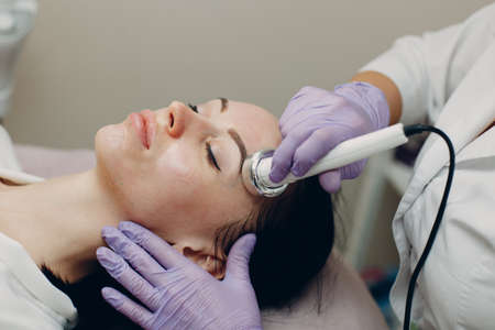 Close up of head woman receiving electroporation phonophoresis facial therapy at beauty spa salonの写真素材