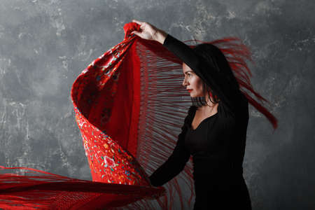 Young adult spanish woman dancing flamenco on gray vintage studio backgroundの写真素材