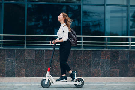 Young woman enjoying riding electric scooter at the city.