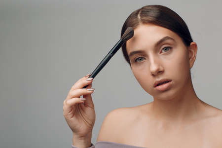 Portrait of young beautiful positive woman with nude make up and brushの写真素材