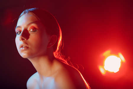 Portrait of young beautiful positive woman with nude make up and colorful light.の写真素材