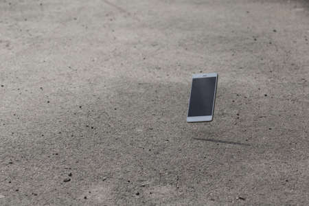 Broken screen mobile phone lies on groundの写真素材