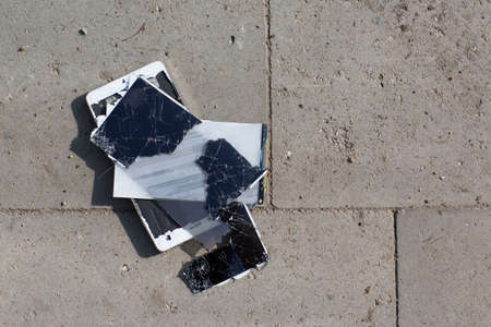 Broken screen mobile phone lies on groundの写真素材