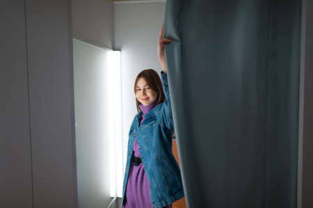 Young woman try on clothes in dressing room with mirror in shop.の写真素材