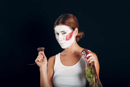 Young woman applying make-up, paints face with painting brush and makeup. How not to do make up concept circus clownの写真素材