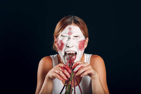 Young woman applying make-up, paints face with painting brush and makeup. How not to do make up concept circus clownの写真素材