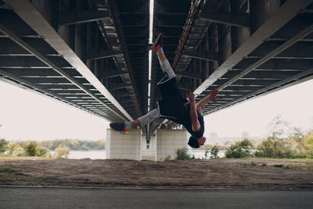 Young sporty guy doing parkour at the city street