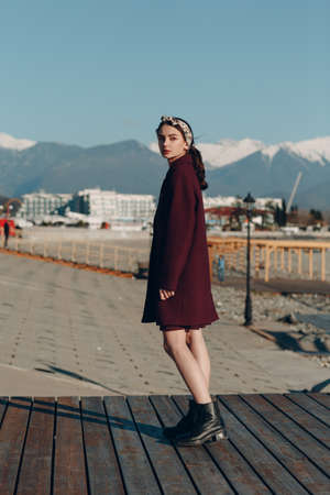 Young woman in coat outdoors on mountain background.の写真素材