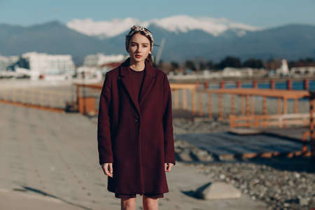 Young woman in coat outdoors on mountain background.の写真素材