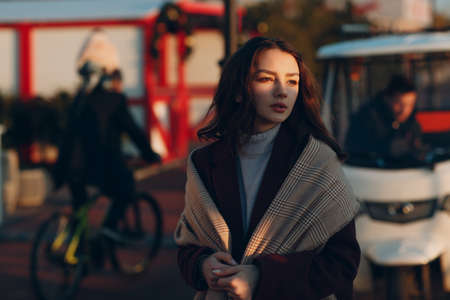 Young woman in coat outdoors eyes sun litの写真素材