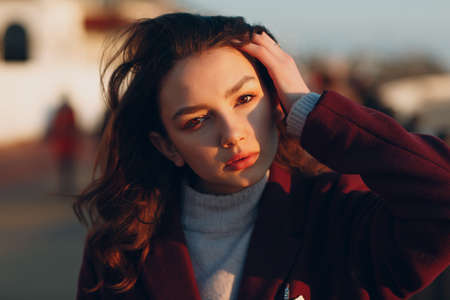 Young smiling brunette woman in coat outdoors portrait.の写真素材