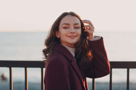 Young smiling brunette woman in coat outdoors portrait.の写真素材