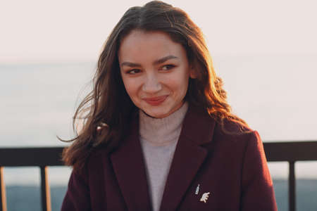 Young smiling brunette woman in coat outdoors portrait.の写真素材