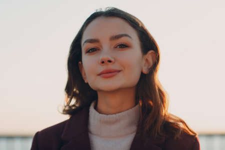 Young smiling brunette woman in coat outdoors portrait.の写真素材