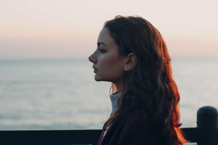 Young smiling brunette woman in coat outdoors portrait.の写真素材