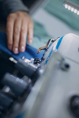 Young beautiful seamstress sews on sewing machine in factory.の写真素材